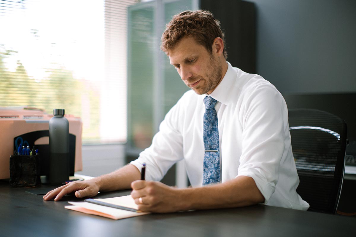 A man sitting a desk writing on a legal pad
